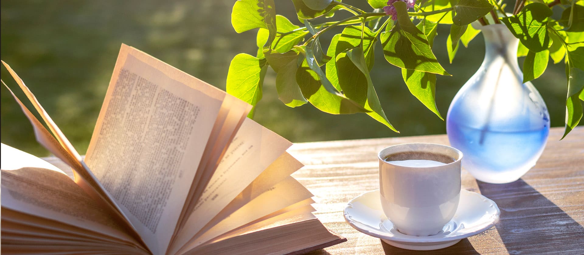 Book, coffee and vase on a table in a garden