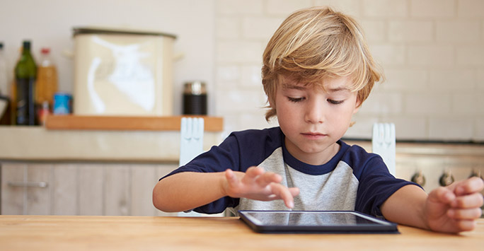Young boy sitting at table with ipad