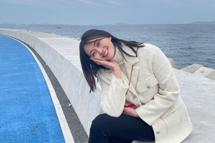 smiling student sat by the sea