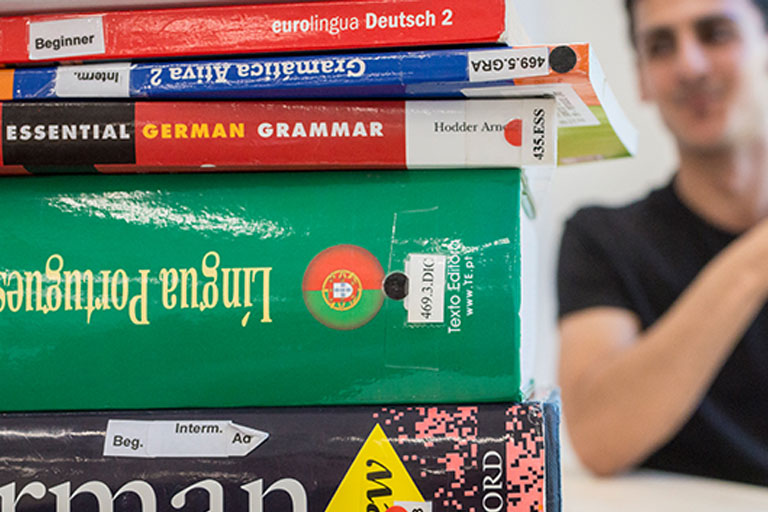 A student with a stack of language grammar dictionaries