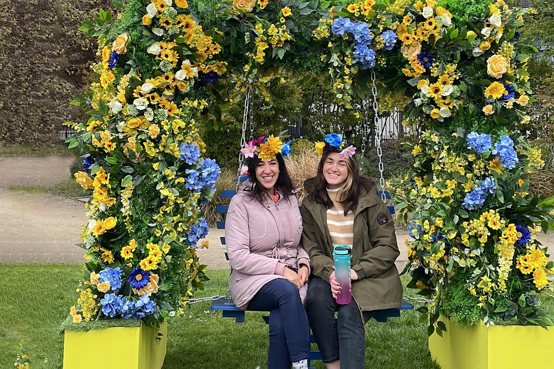 Two students sitting on a bench surrounded by flowers