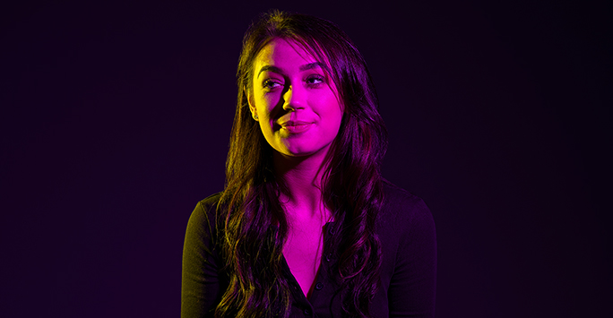 Colourful photograph portrait of a student with long dark hair against a black background