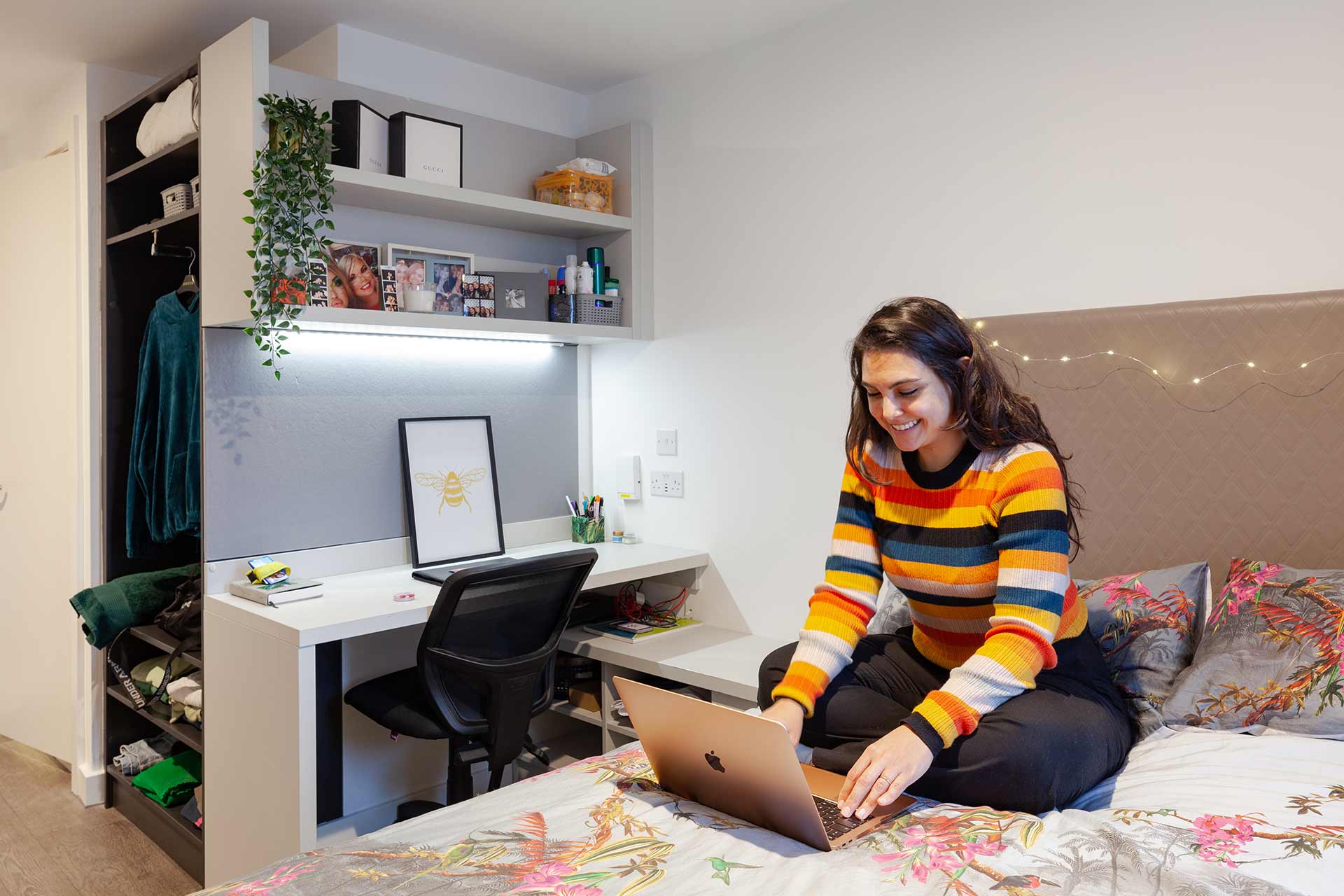 A student working on a Macbook while sat on a bed in a True Student Double Ensuite bedroom.