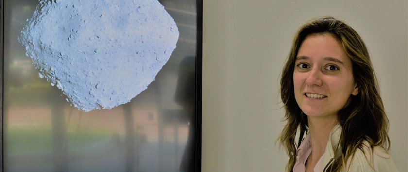 female scientist beside image of asteroid