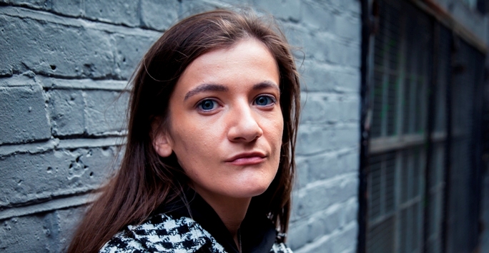 woman against grey wall looking into camera