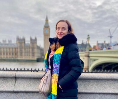 woman in coat and scarf with Houses of Parliament in background