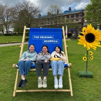 students sitting on large deckchair in park