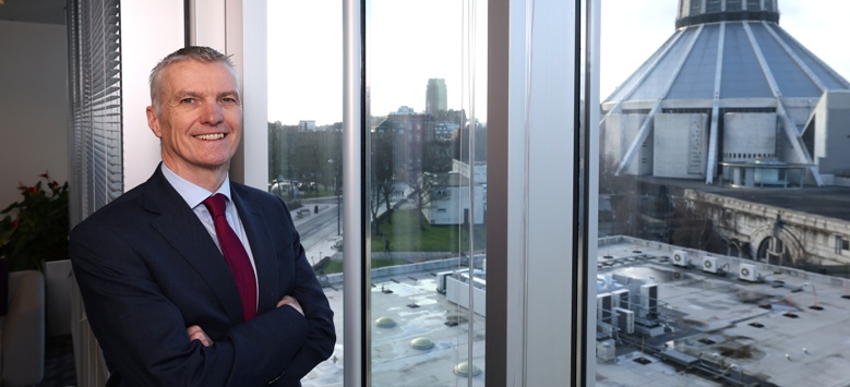 man standing with folded arms beside window
