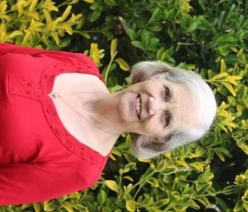 woman in red top in front of shrubbery