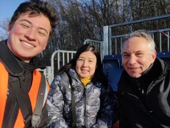 woman and two men in winter jackets smiling at camera