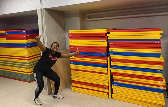 A student next to a pile of judo mats