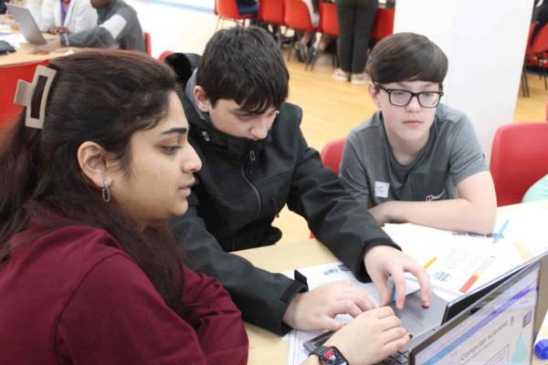 A group of people sitting at a table looking at a computer
