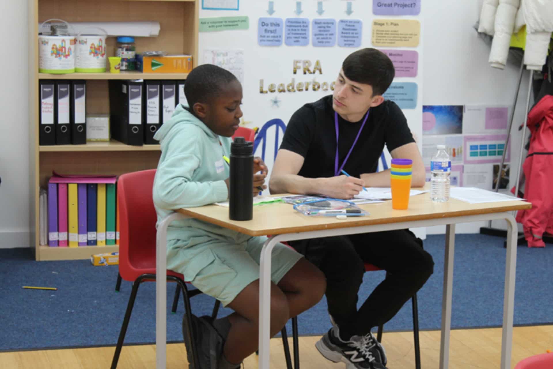 A school child and student sitting at a tables at the IntoUniversity Centre