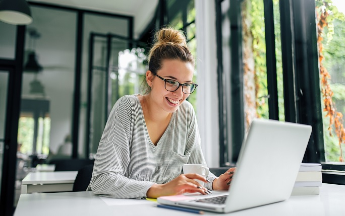 Student smiling whilst looking at laptop