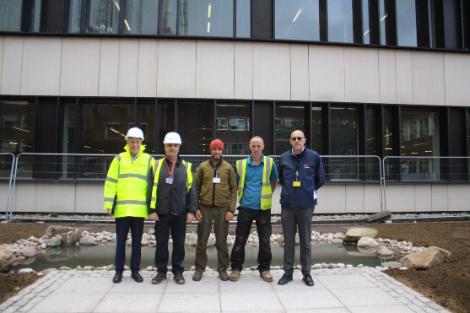 Unviersity staff standing in front of the pond construction