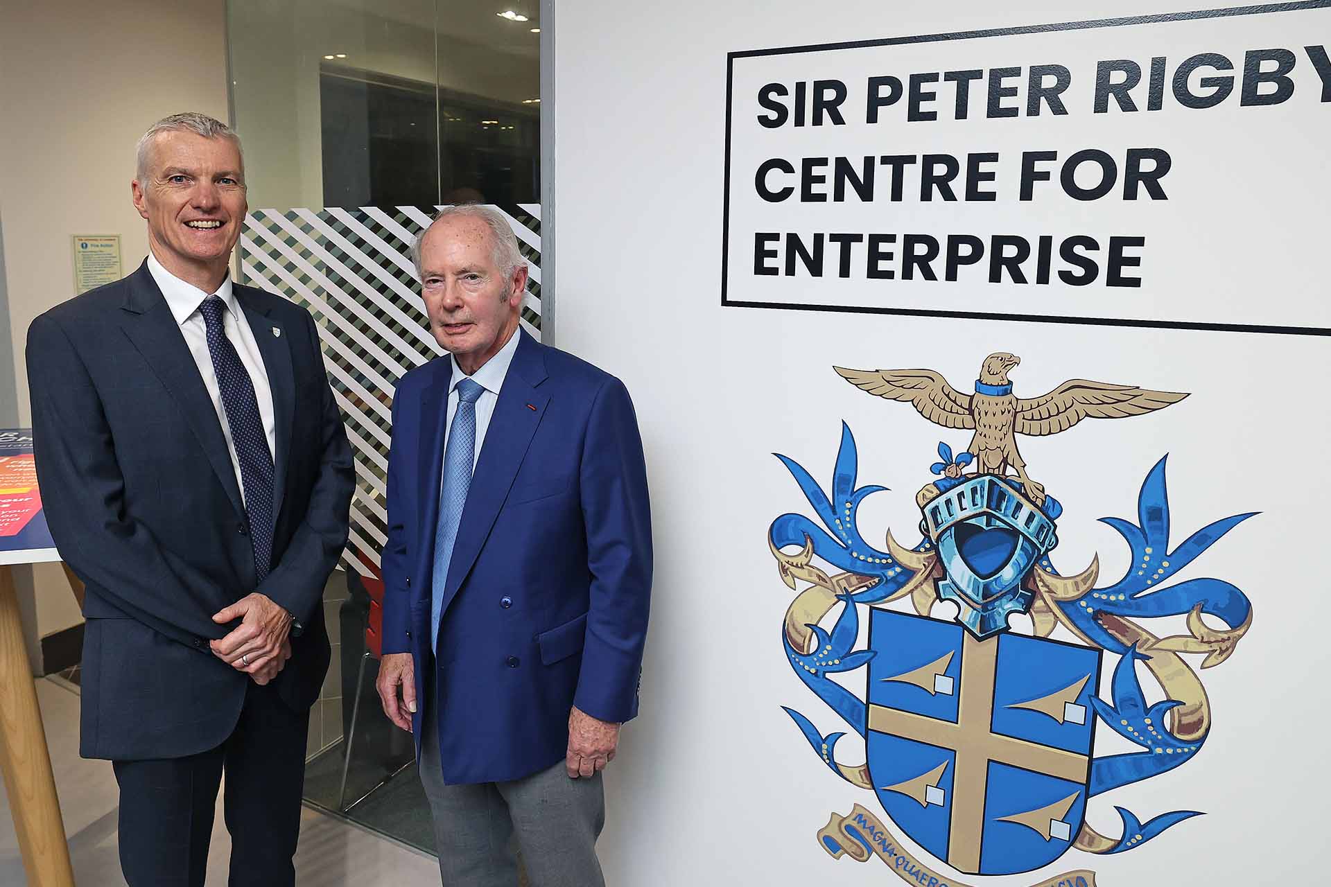 Two people in front of a sign that reads: Sir Peter Rigby Centre for Enterprise