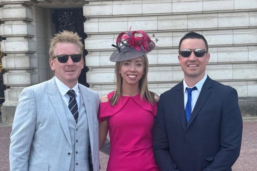 Three people outside Buckingham Palace