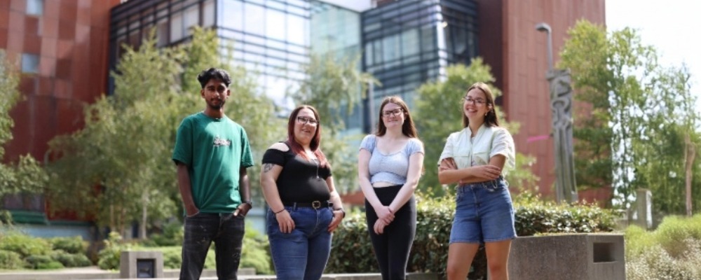 Four students standing together smiling