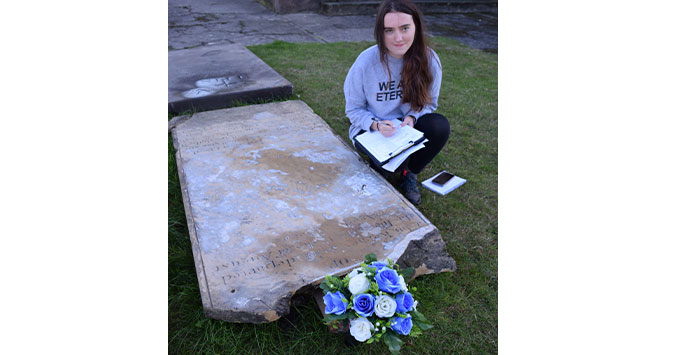 a student records a memorial uncovered by parish volunteers