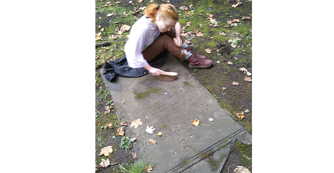 student cleaning a memorial before recording it