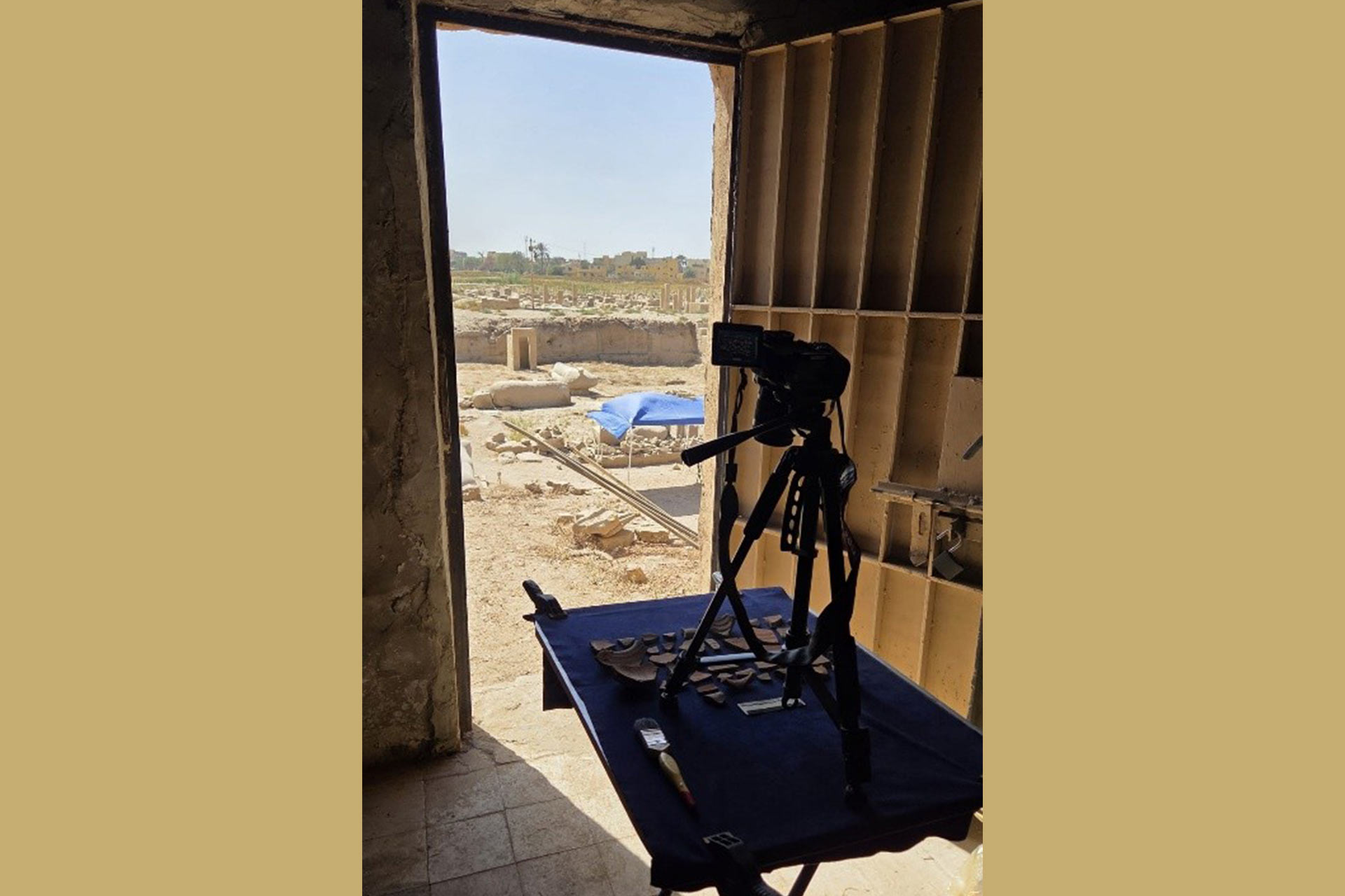 A table with Archaeological artefacts on it and a tripod with a camera set up to capture them.
