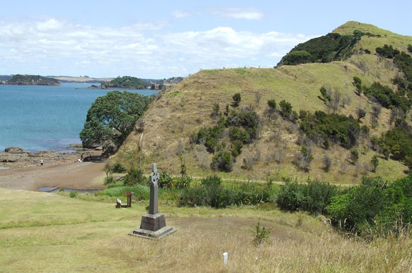 Rangihoua pā overlooking the Oihi mission site on the terrace in the foreground; the monument celebrates Marsden’s first Christian service on New Zealand soil.