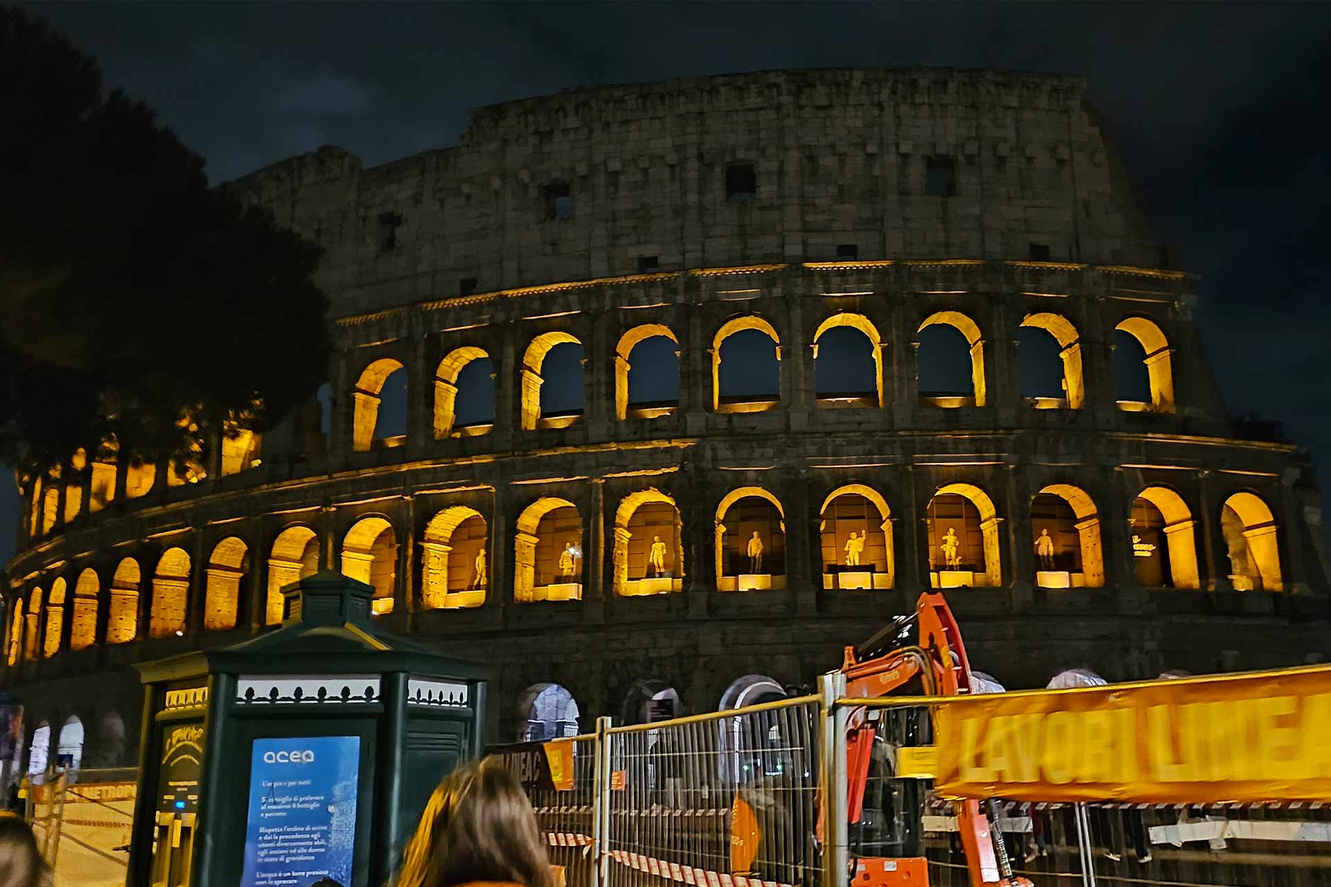 A colosseum at night time illuminated from within with warm coloured lights