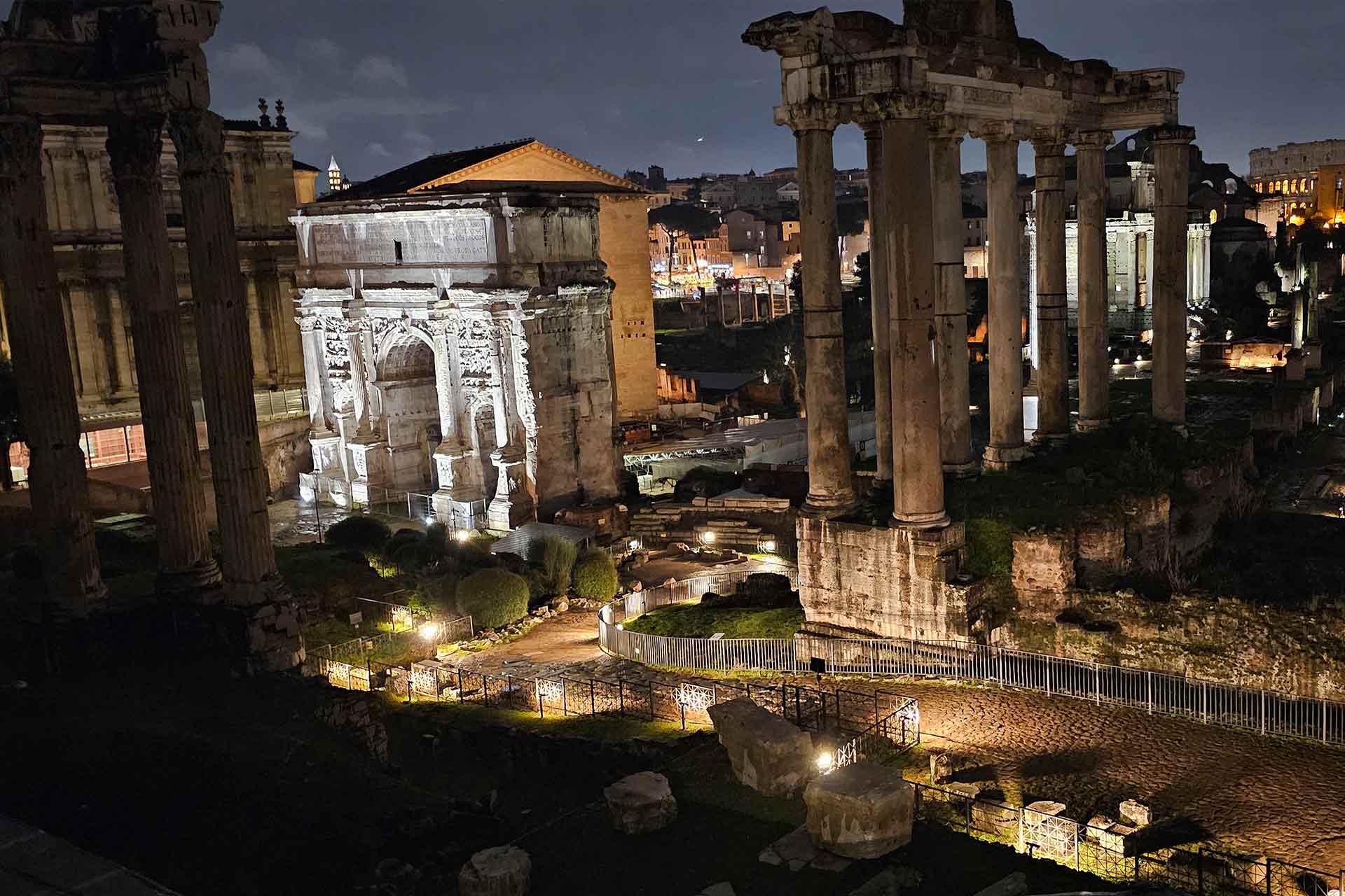 Old Roman ruins and columns in between an archway at night, illuminated by spotlights