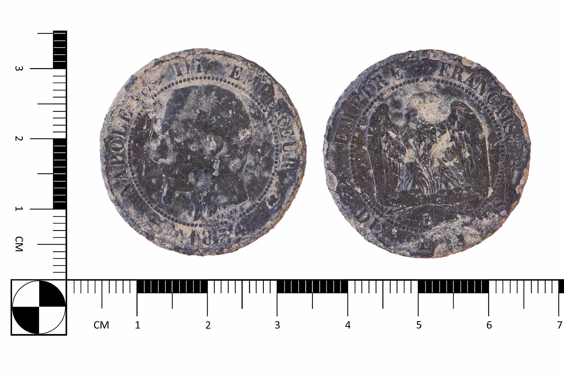 A dark silver coin in front of a ruler showing it to be 3.4cm wide and 3.4cm tall.