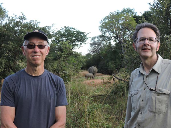 Two men in Zambia, rhinos behind