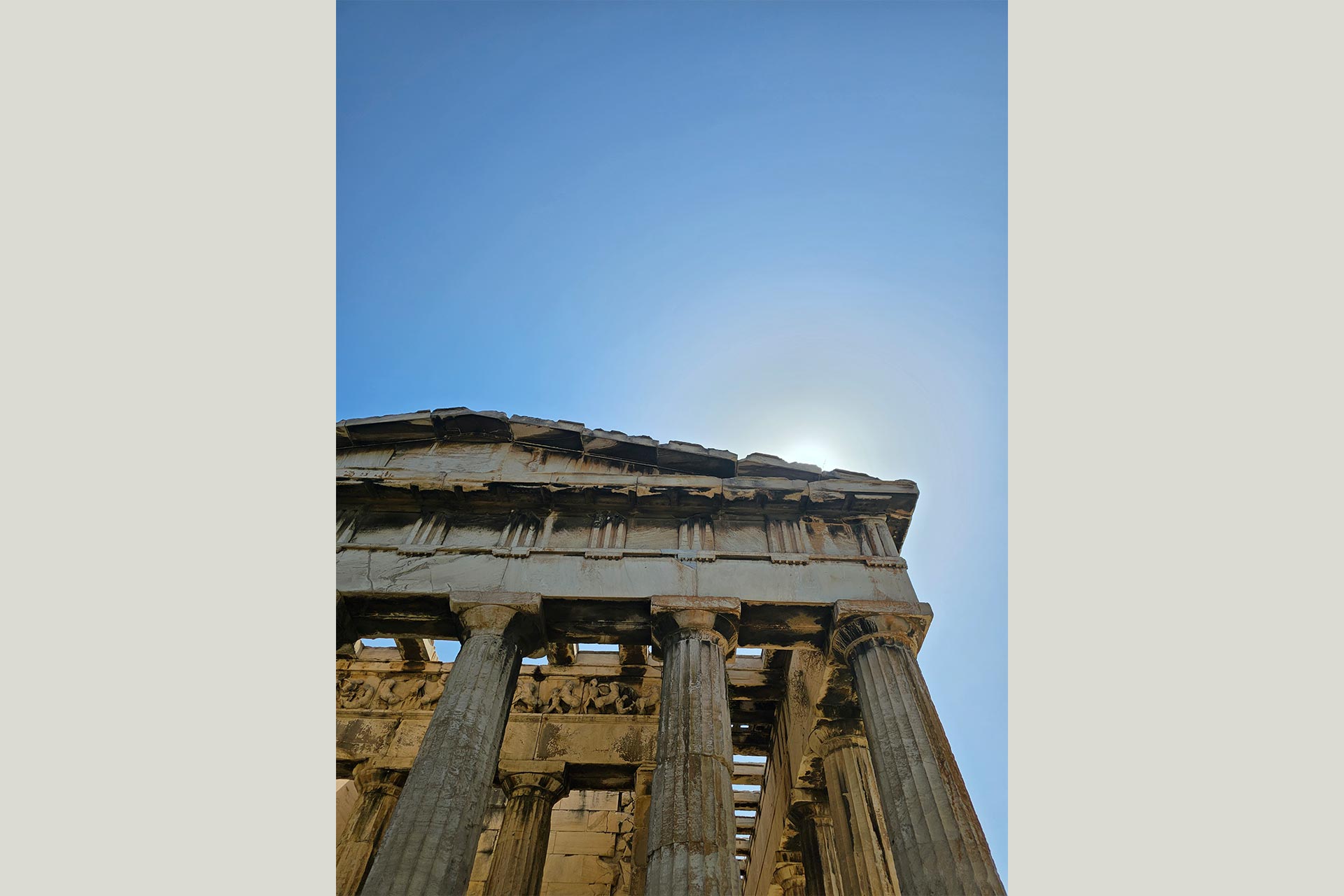 Top corner of an ancient Greek building with large columns.