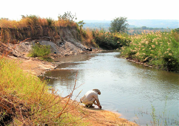 Archaeologist digging at a river