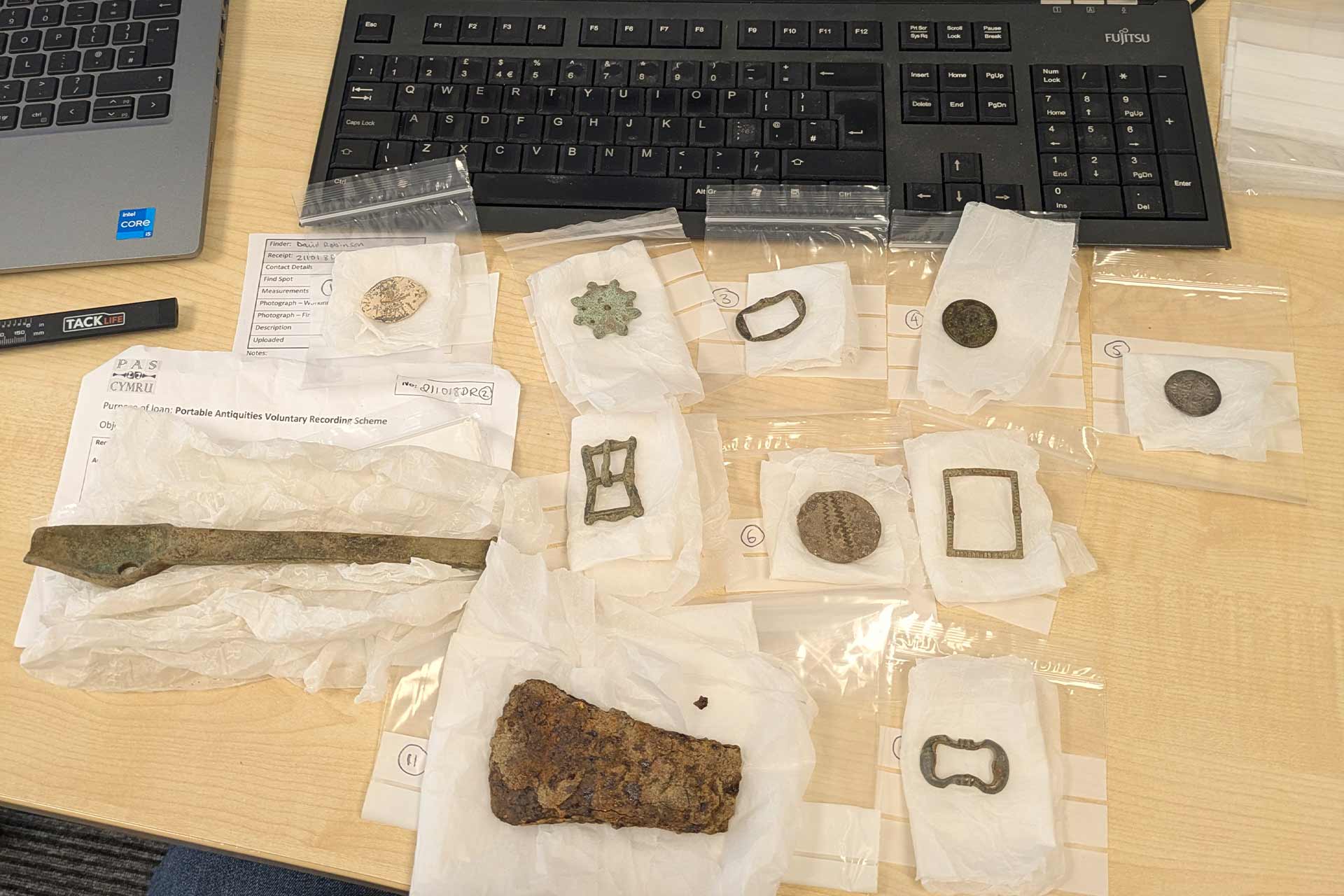 A selection of small old archaeological artifacts in plastic bags on a table.