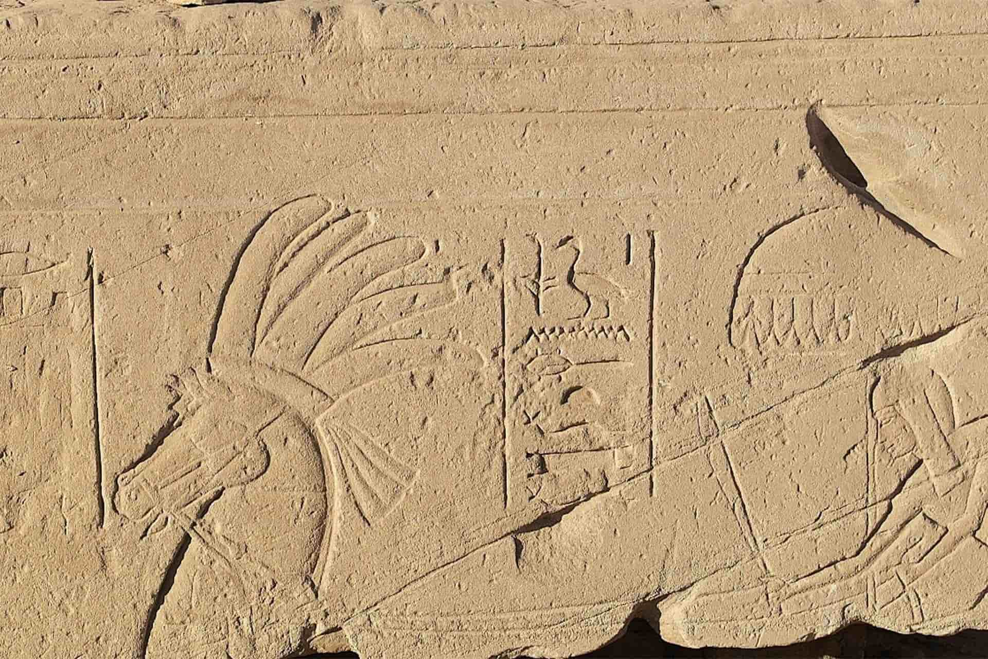 An ancient stone with carved figures on it including a horse and hieroglyphics.