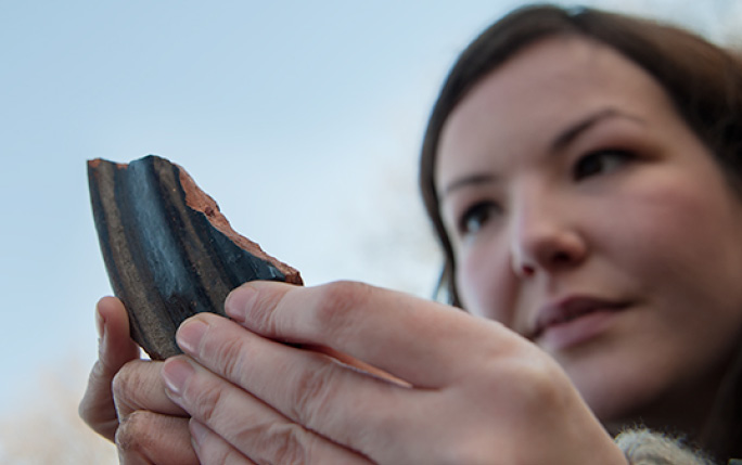 A woman holds a fragmented piece of archaeological material