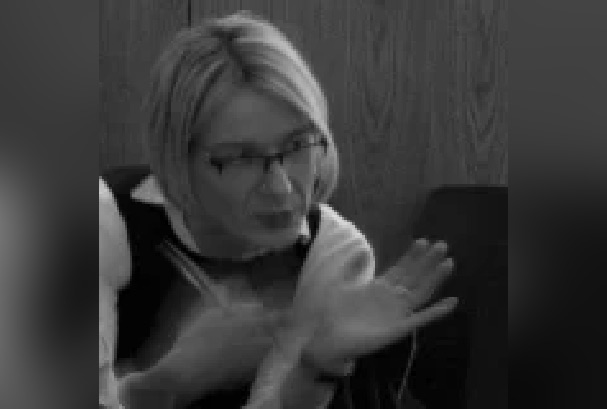 BLack and White image of a woman with short bobbed hair and wearing glasses. She is gesticulating with her hands