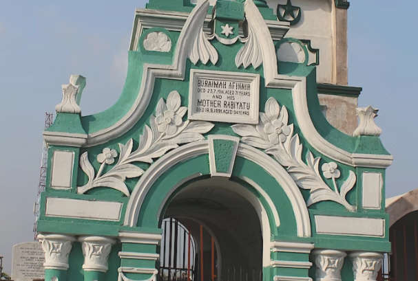 Funereal arch decorated with columns and floral relief. Text on a plaque in the middle commemorates Buraimah Afinnia, died 23.7.1914 aged 71 years, and his Mother Rabiyatu, died18.8.1891 aged 94 years.