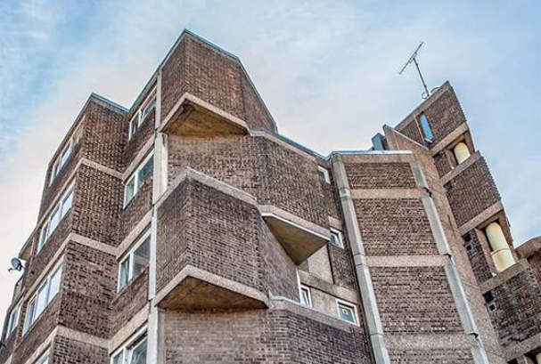 Brick built block of flats looked at from below against a blue sky