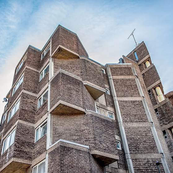 Brick built block of flats looked at from below against a blue sky