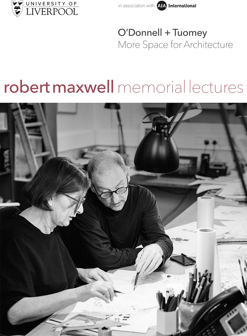 A white man and a white woman sitting at a desk discussing an architectural plan