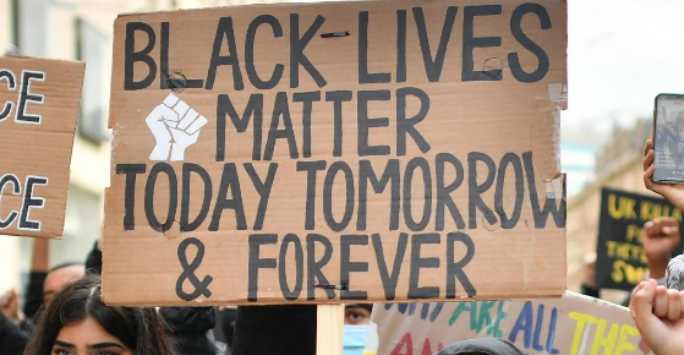 Cardboard placards at a street protest, one reads 