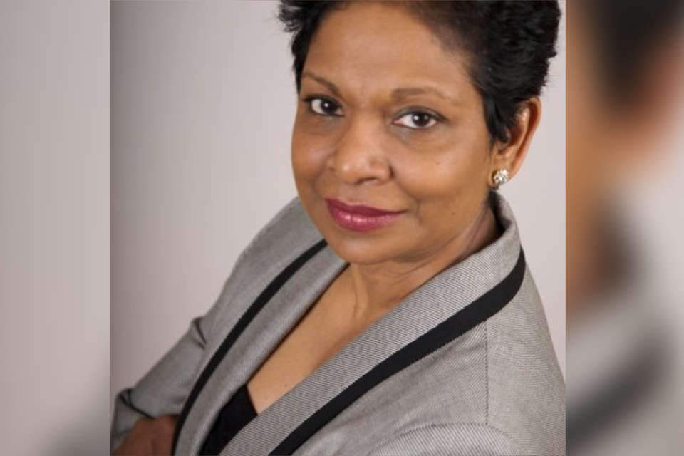 3/4 view of a business woman looking up at a camera. She is wearing a smart suit and has short hair.