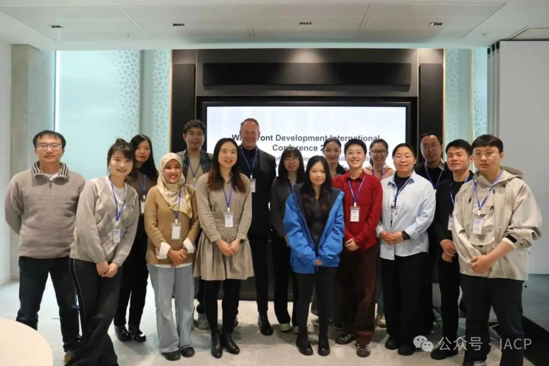 A mixed group of delegates standing in front of a screen and posing for the camera.