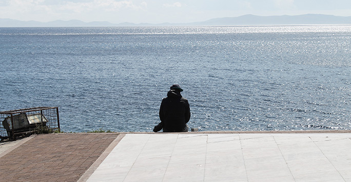 A refugee is looking back towards the shores of Turkey where he came from.