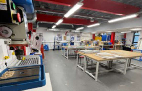 Workshop with tables on the right hand side of the room and model making machines on the left.