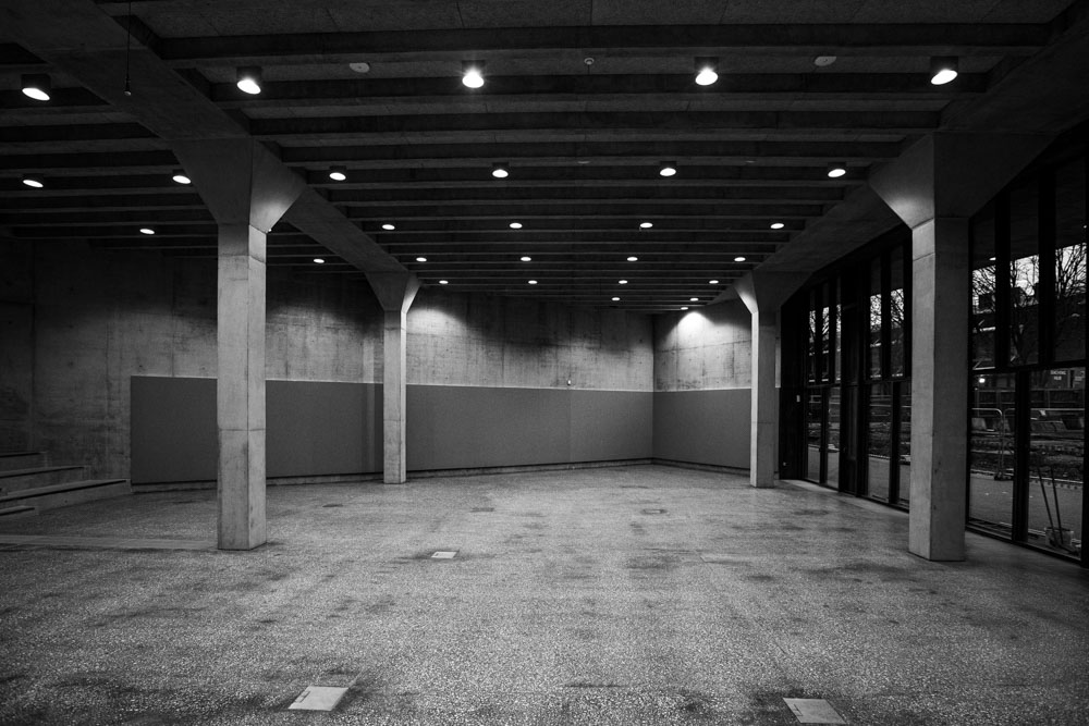 Interior of an empty contemporary exhibition space with concreter walls, pillarsa nd floor.