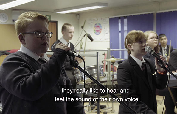 Two d/Deaf students singing into microphones, overlaid caption 
