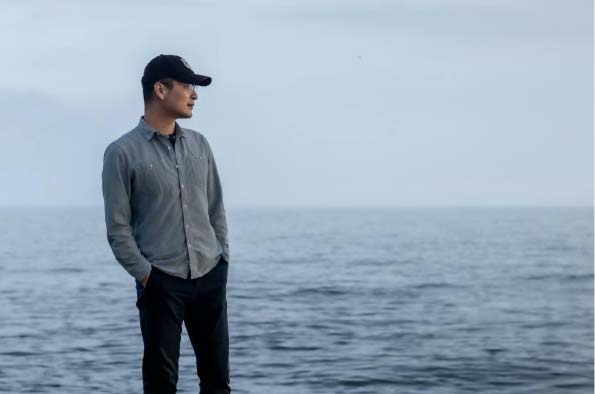 Dr Wei Zhao standing in front of the sea and looking to the horizon