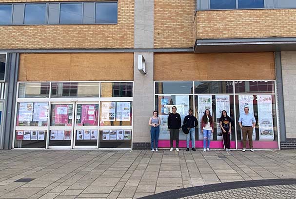 Students with posters displayed in shop windows
