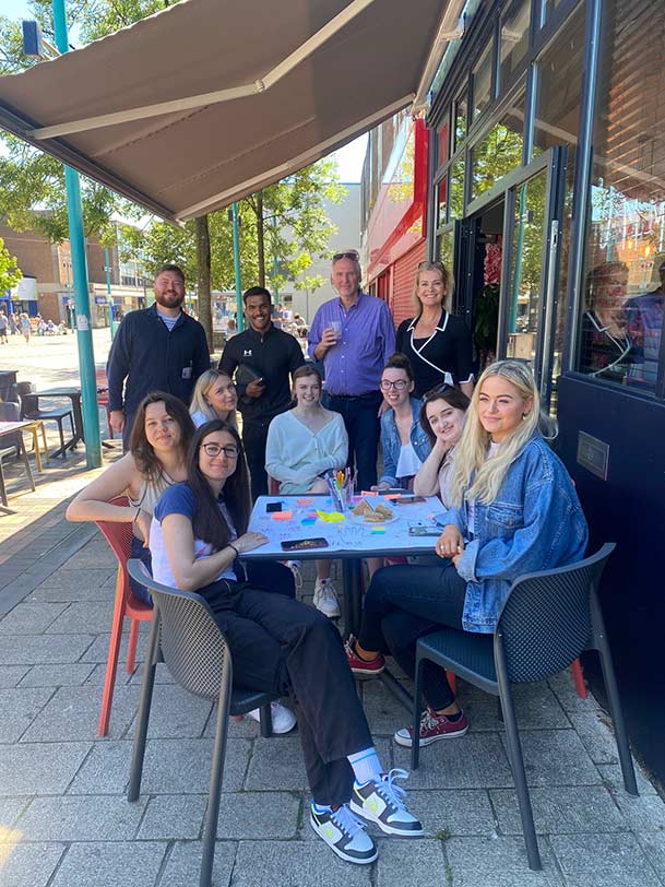 STaff, students and stakeholders sitting outside at a street café
